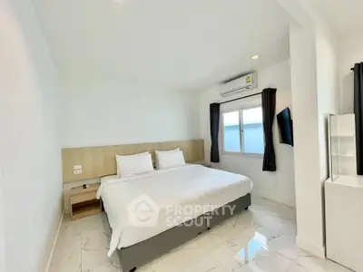 Modern bedroom with king-size bed, air conditioning, and sleek white decor