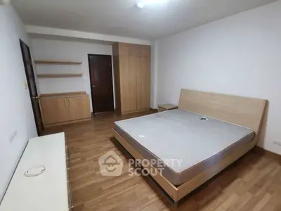 Spacious bedroom with wooden flooring and modern furniture in a stylish apartment.