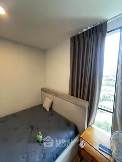 Cozy bedroom with plush bed and large window offering natural light and city view.