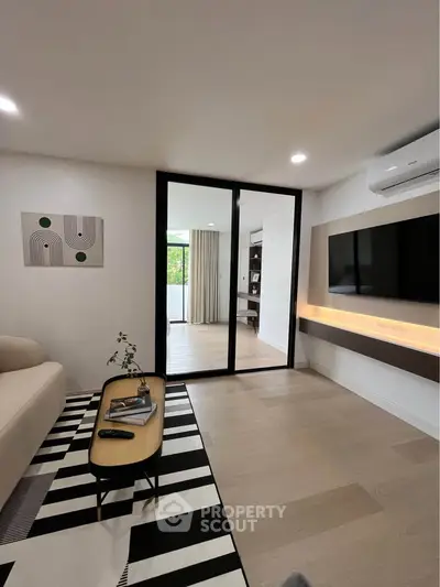 Modern living room with sleek design, featuring a wall-mounted TV, stylish furniture, and elegant decor.