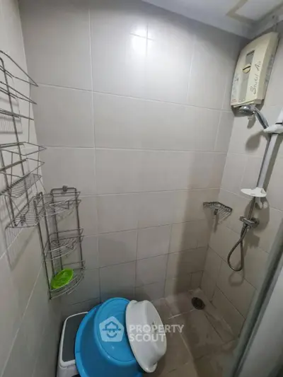 Compact bathroom with shower and water heater in modern apartment.