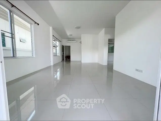 Spacious empty living room with glossy tiled floors and large windows.