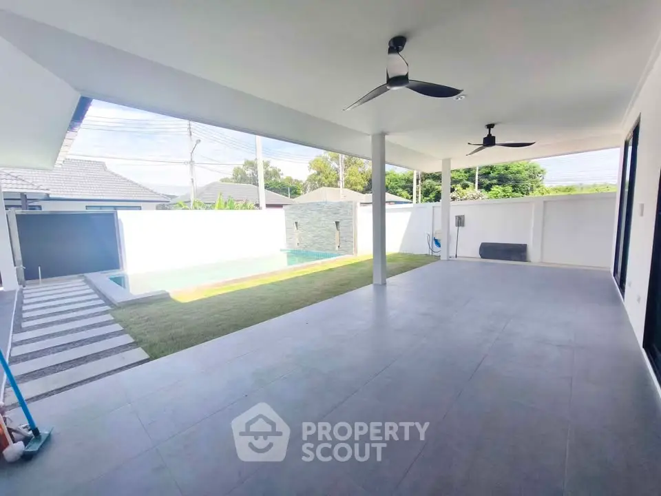 Spacious covered patio with ceiling fans overlooking a private pool and garden area.