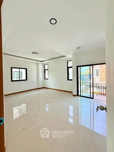 Spacious unfurnished living room with large windows and balcony access in modern apartment.