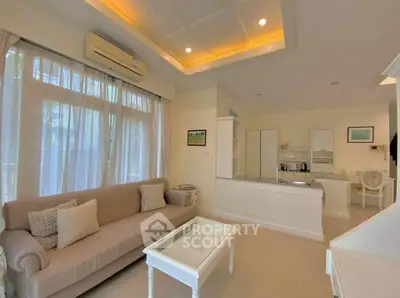 Charming living room with elegant sofa and open kitchen layout, featuring modern lighting and large windows.