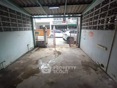 Spacious garage with gated entrance and concrete flooring in urban setting.