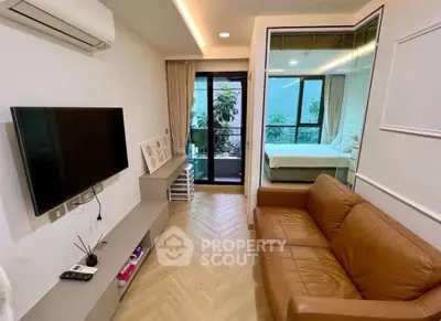 Modern living room with brown leather sofa, wall-mounted TV, and balcony view in stylish apartment.