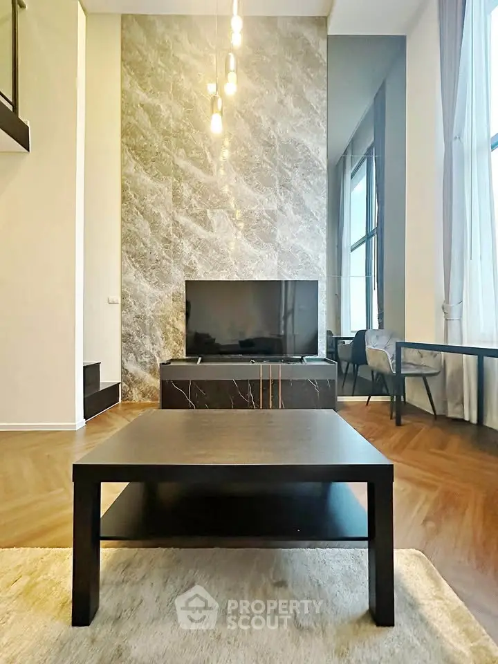 Luxurious living room with high ceilings, elegant marble wall, and modern furnishings.