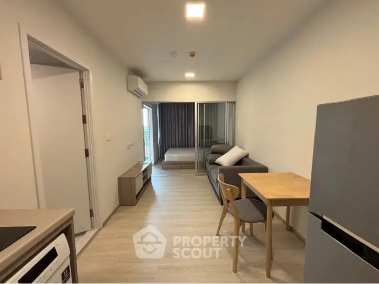 Modern open-plan living room with dining area and bedroom in a compact apartment.