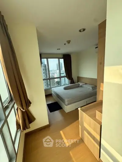 Spacious bedroom with large windows offering stunning city views in modern apartment.