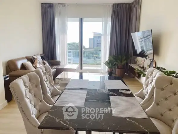 Elegant living room with dining area and modern decor, featuring a large window with a view.