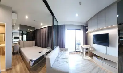 Modern studio apartment with open layout, featuring a cozy living area, sleek kitchen, and large windows for natural light.