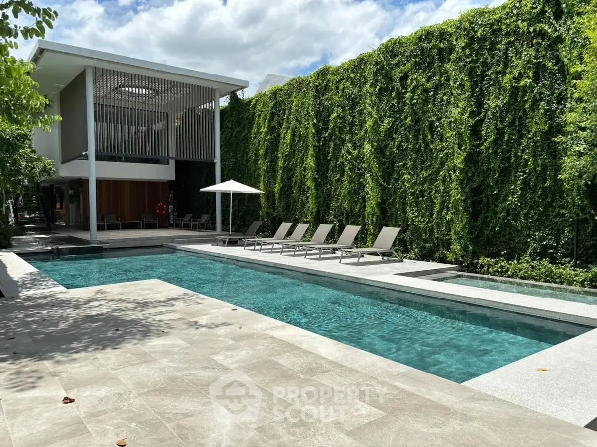 Luxurious modern pool area with lush greenery and stylish lounge chairs, perfect for relaxation and entertainment.