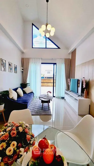 Spacious modern living room with high ceiling and large windows, elegant decor and natural light.
