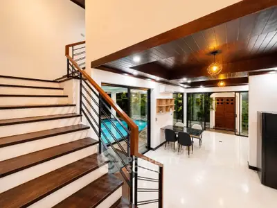 Modern open-concept living area with stylish staircase and pool view, perfect for luxury living.