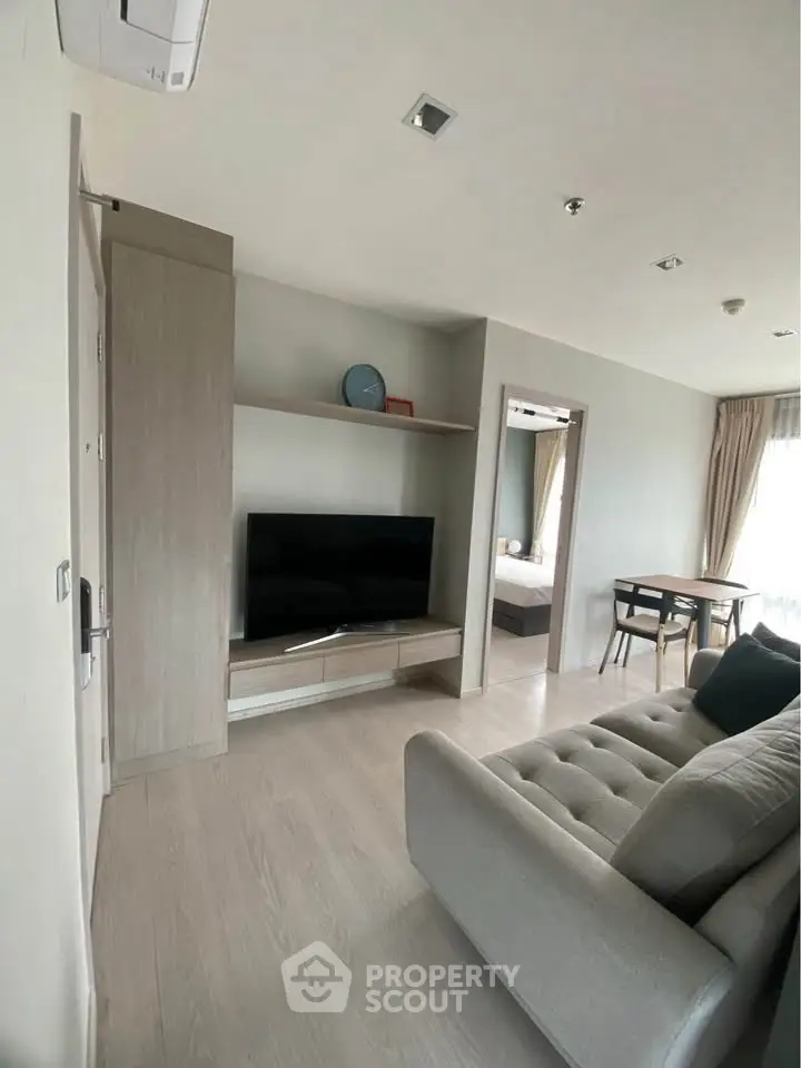 Modern living room with sleek design, featuring a cozy sofa and flat-screen TV, perfect for relaxation.