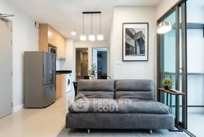Modern living room with sleek kitchen and stylish decor in open layout apartment.