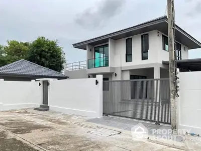 Modern two-story house with sleek design and gated entrance in suburban neighborhood.