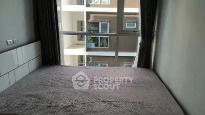 Cozy bedroom with large window offering a view of the neighboring building, perfect for urban living.