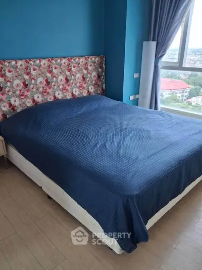 Cozy bedroom with floral headboard and large window offering scenic views.