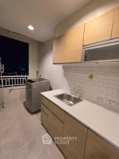 Modern kitchen with sleek cabinetry and city view, featuring a washing machine and ample counter space.