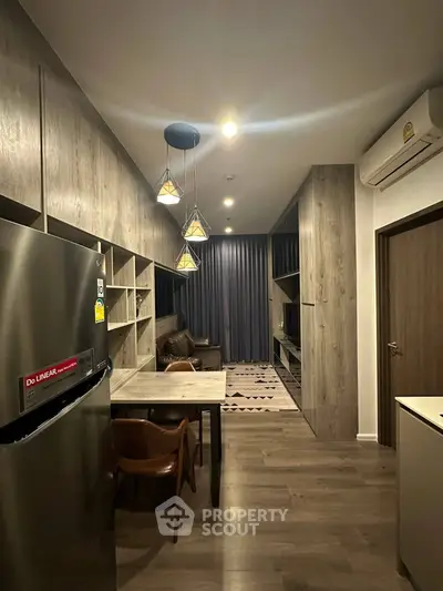 Modern living room with stylish lighting and open layout, featuring a cozy dining area and sleek wooden flooring.