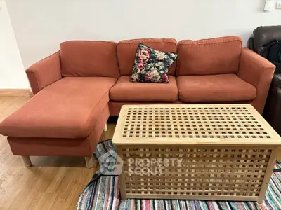 Cozy living room with stylish orange sofa and wooden coffee table on a colorful rug.