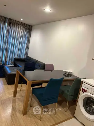 Modern living room with dining area and washing machine, featuring sleek furniture and wooden flooring.