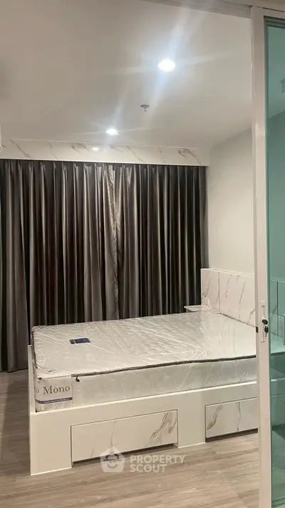 Modern bedroom with sleek design and large window, featuring a stylish bed and elegant curtains.