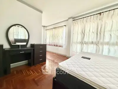 Spacious bedroom with elegant parquet flooring and ample natural light