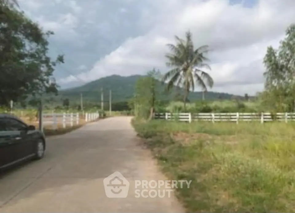 Scenic rural road with mountain view and lush greenery, ideal for tranquil living.