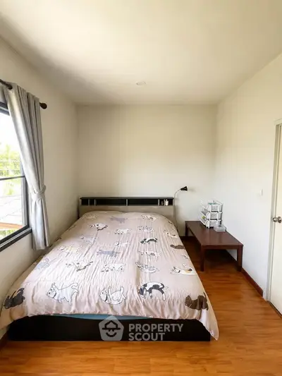 Cozy bedroom with wooden flooring and natural light from window