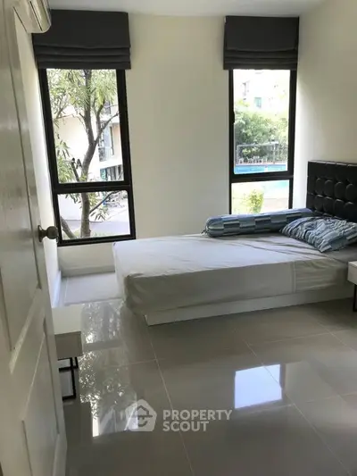 Bright bedroom with large windows and modern furnishings in a stylish apartment.