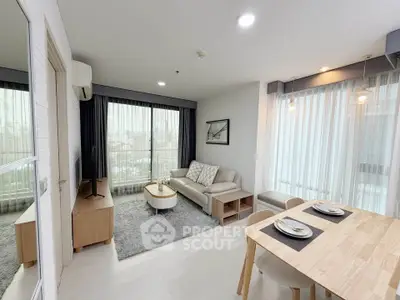Modern living room with dining area, large windows, and stylish decor in a high-rise apartment.