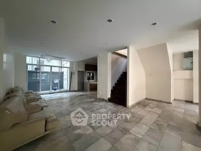 Spacious modern living room with tiled flooring and staircase, perfect for family gatherings.