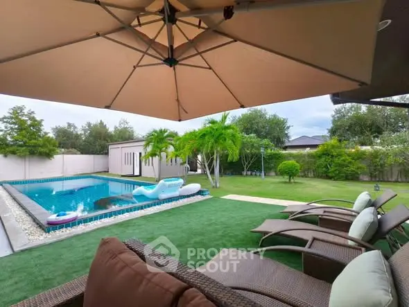 Luxurious backyard with pool, lush garden, and stylish patio furniture under a large umbrella.