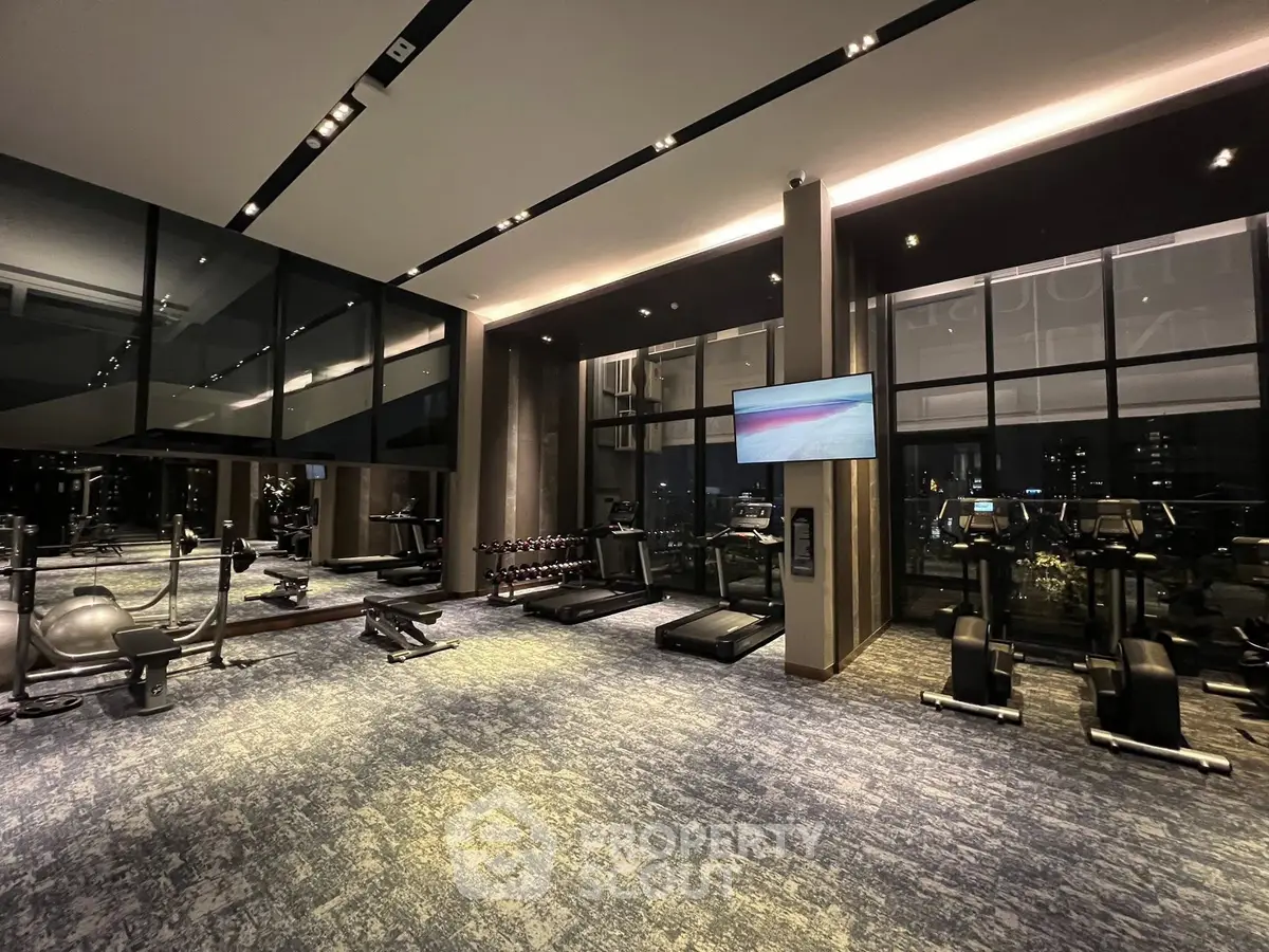 Luxurious gym with modern equipment and floor-to-ceiling windows offering stunning views.