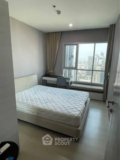 Modern bedroom with city view, featuring a comfortable bed and stylish decor.