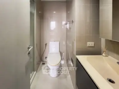 Modern bathroom with sleek fixtures and neutral tiles, featuring a shower and vanity.