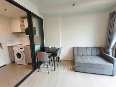 Modern apartment with open layout, featuring a cozy living area and a compact kitchen with washing machine.