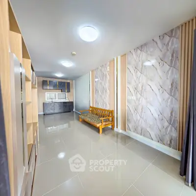 Spacious modern living room with elegant marble accent wall and sleek tile flooring.
