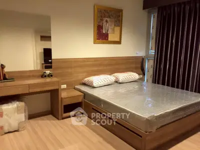 Modern bedroom with wooden furniture and large window for natural light.