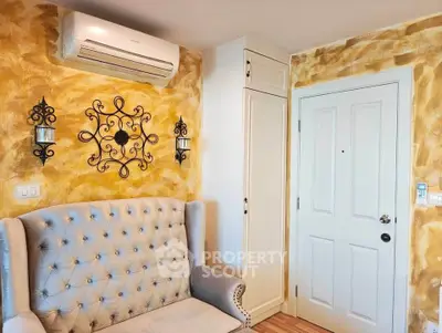 Charming living room with elegant wall decor and plush seating, featuring a modern air conditioning unit.