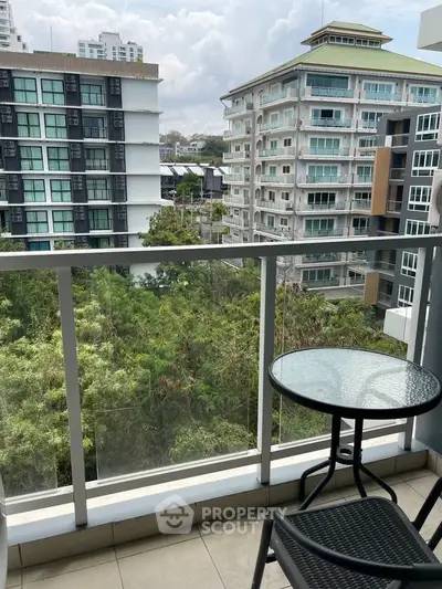 Charming balcony with glass railing offering lush green views in a modern urban setting.