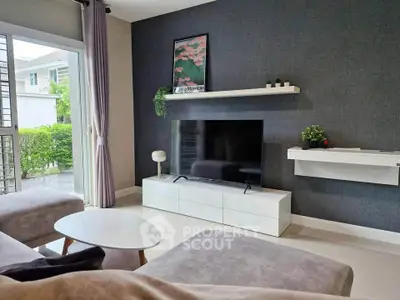Modern living room with sleek furniture and large TV, featuring a stylish open layout and natural light.
