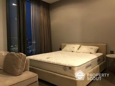 Elegant bedroom with a large comfortable bed, plush headboard, and a cozy sitting area by the window, offering a serene urban view.