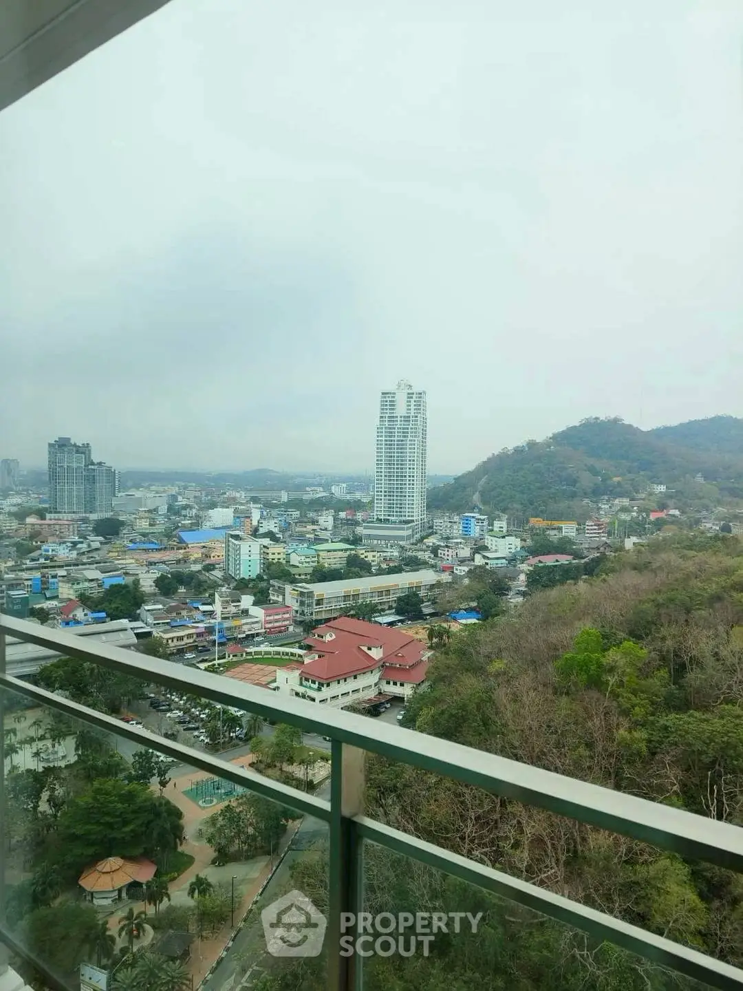 Stunning cityscape view from high-rise balcony overlooking urban skyline and lush greenery.