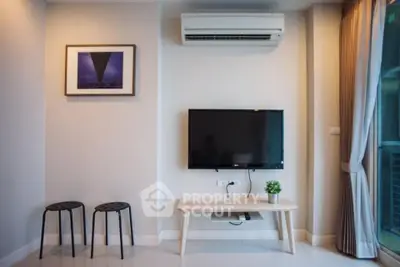 Modern living room with wall-mounted TV and air conditioning, featuring minimalist decor and natural light.