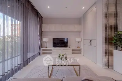 Modern living room with large windows, stylish furniture, and natural light.