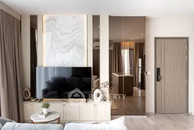 Modern living room with stylish decor and large TV, featuring elegant marble accent wall.